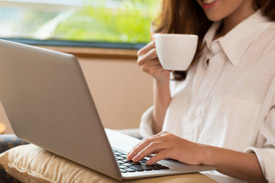 Woman sipping coffee at laptop